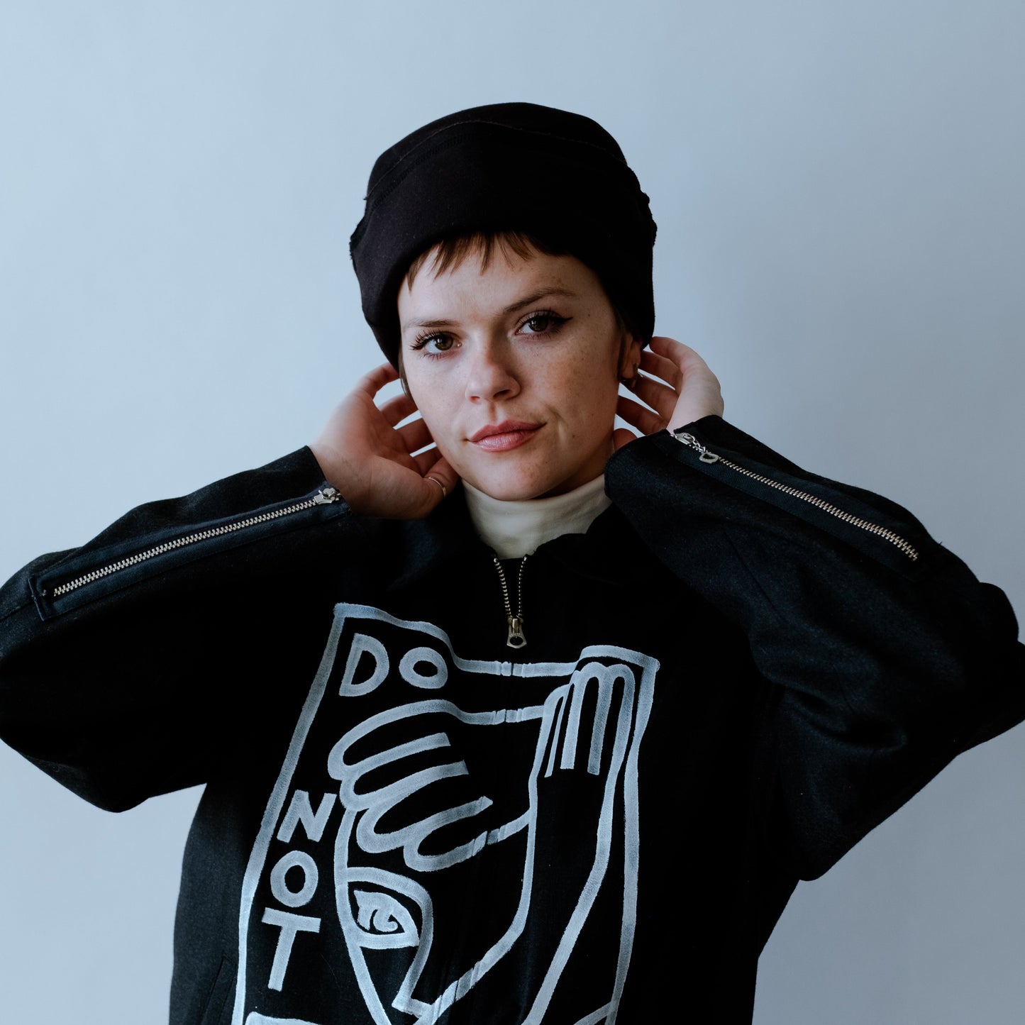 model facing forward with hands on their head wearing a black cuffed cap