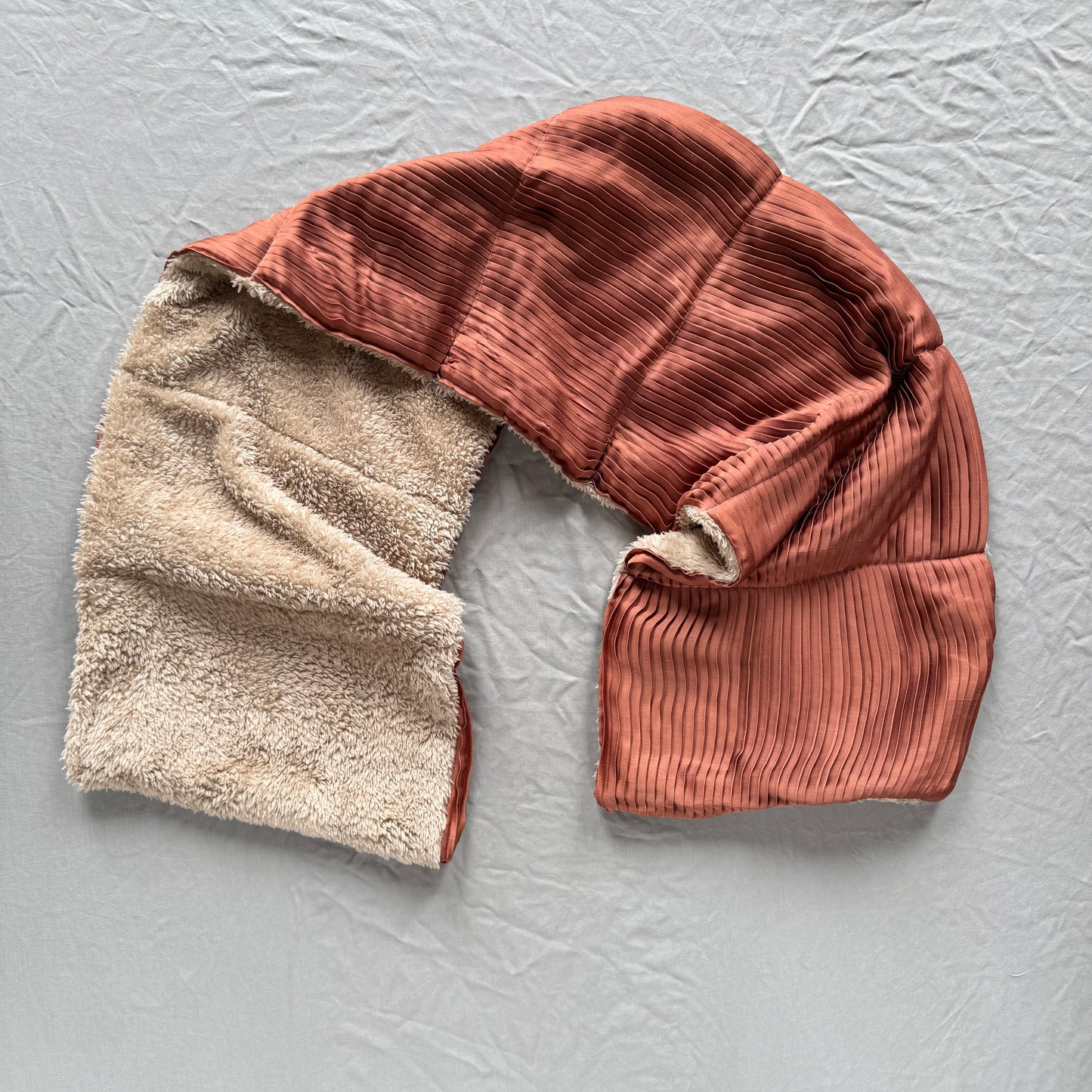 pink pleated silk scarf with fluffy beige fleece on a textured grey background