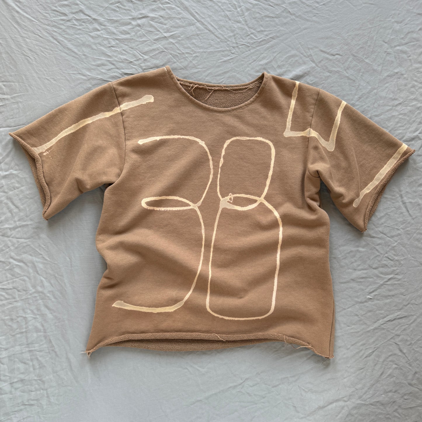 camel colored french terry short sleeved sweat shirt with bleached 11385 across the front and sleeves