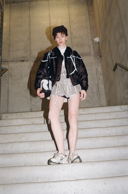 Person wearing a black jacket and white outfit on stone steps.