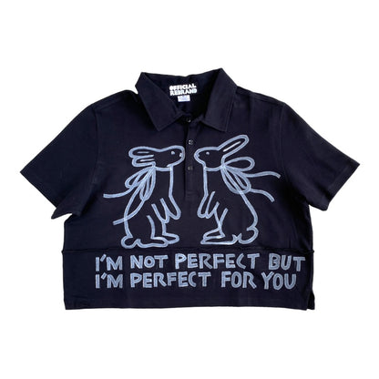 cropped black collared polo shirt with two white hand painted rabbits facing each other and white text reading I'M NOT PERFECT BUT I'M PERFECT FOR YOU