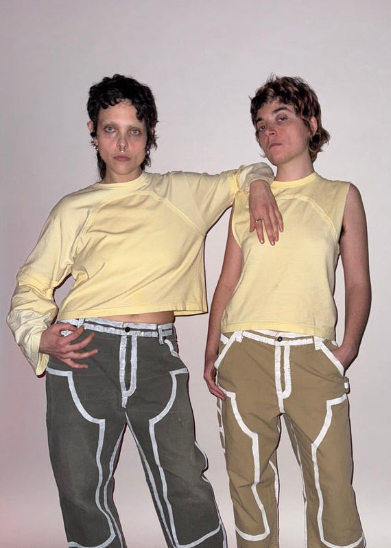 Two people wearing matching outfits with yellow tops on a plain background