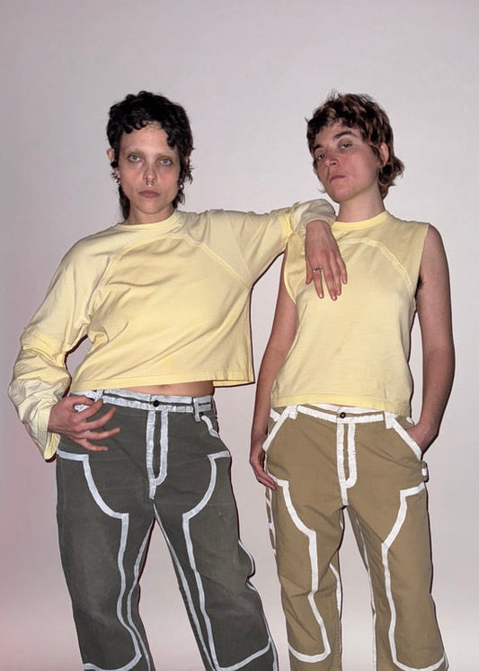 Two people wearing matching outfits with yellow tops on a plain background