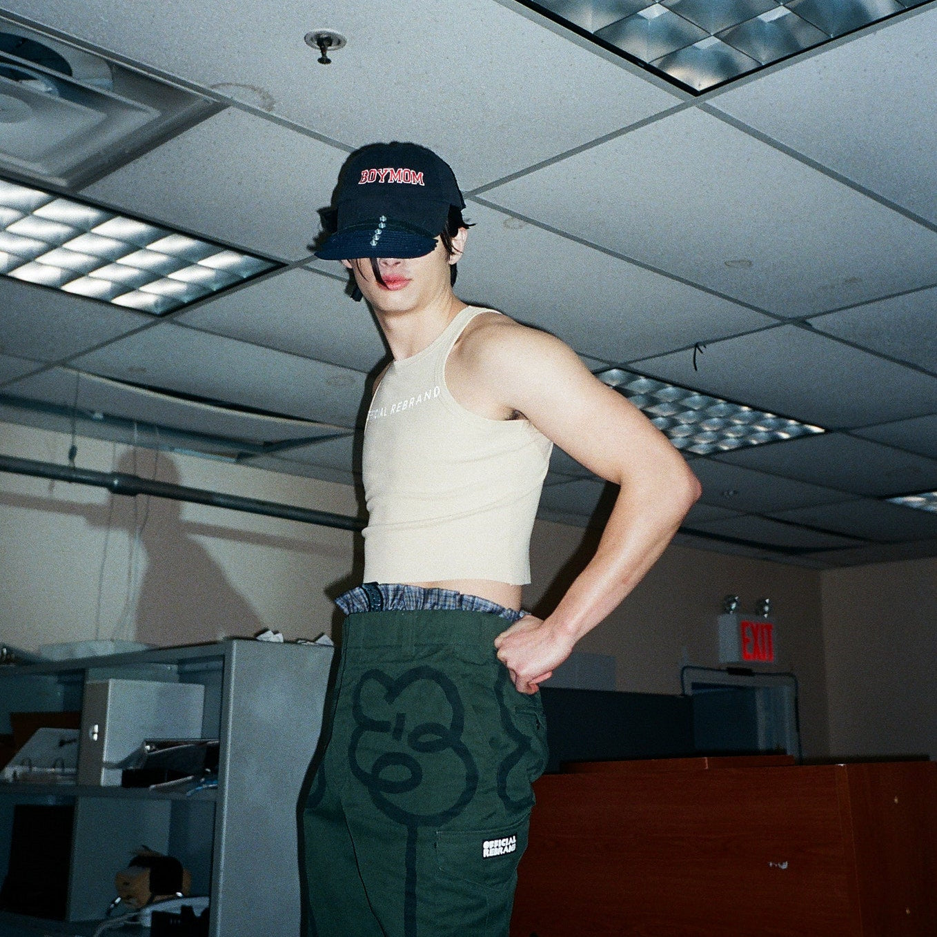 Person wearing a cap and tank top in an indoor setting with office furniture.