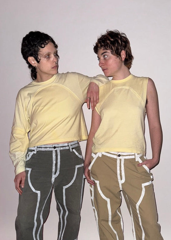 Two people wearing matching outfits with yellow shirts and seam outlined pants on a plain background