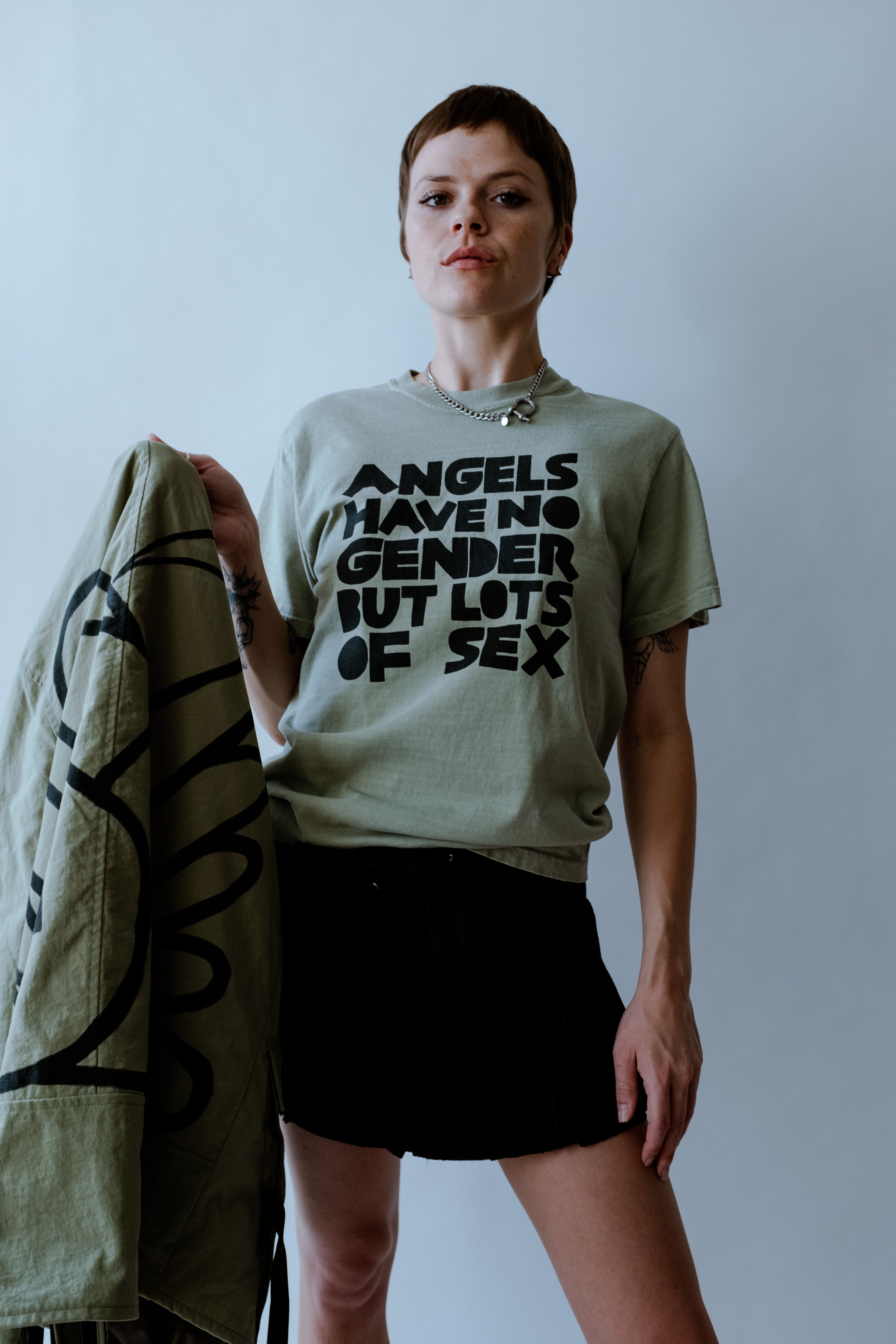 model wearing a green t-shirt with black text reading Angels have no gender but lots of sex