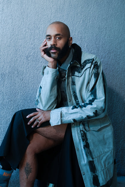 model sitting and wearing long gray duster hand painted with thick black lines