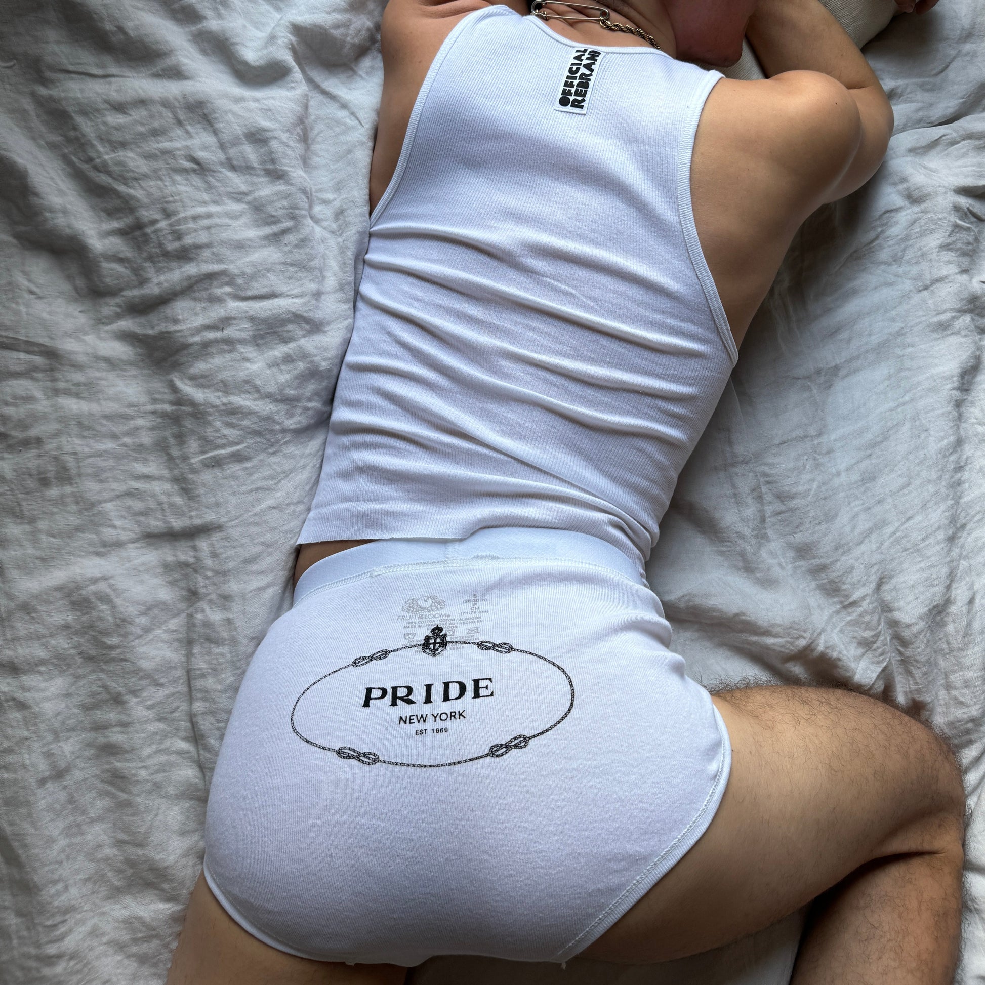 model wearing white briefs with screen printed PRIDE text mimicking the prada logo on the back