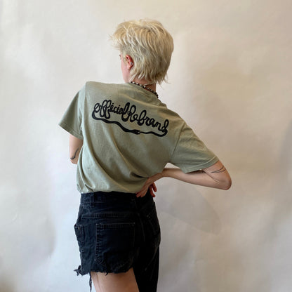 model facing away wearing a light green t-shirt with black ouroboros Official rebrand logo design on the back