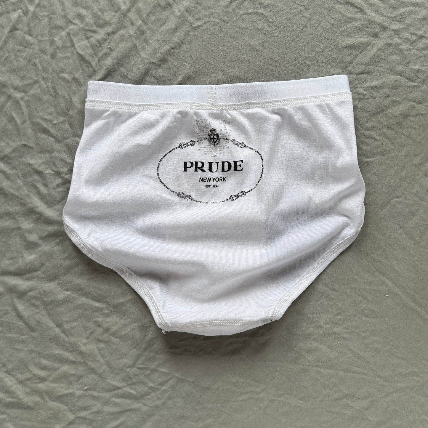 white underwear briefs with hand printed text reading PRUDE in the Prada logo font