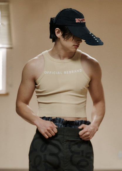Person wearing a beige tank top and black cargo pants in an indoor setting