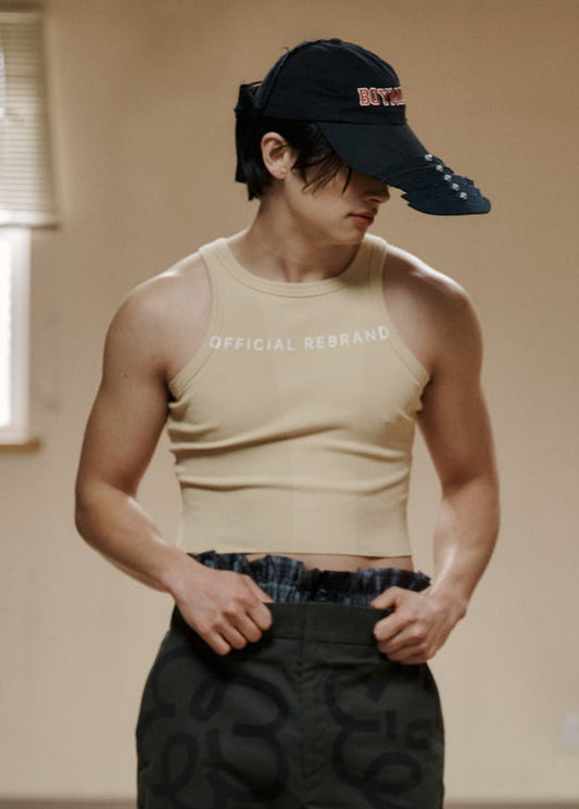 Person wearing a beige tank top and black cargo pants in an indoor setting
