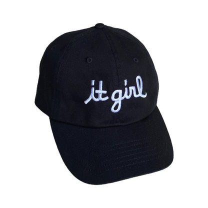 black baseball cap with white embroidery reading it girl in cursive text across the front