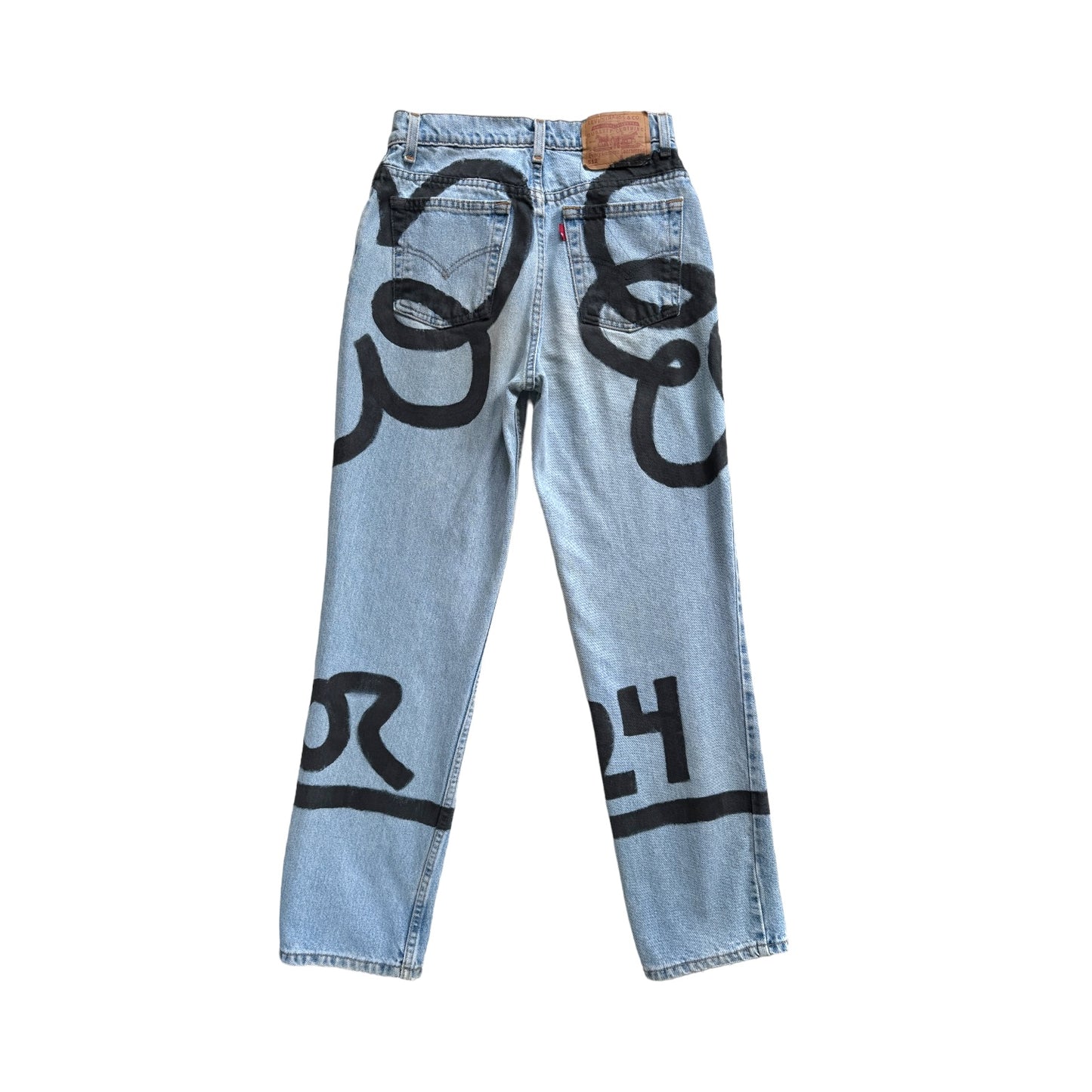 back of Denim pants with two large black flowers and stems painted across the front, sides, and back of the pants