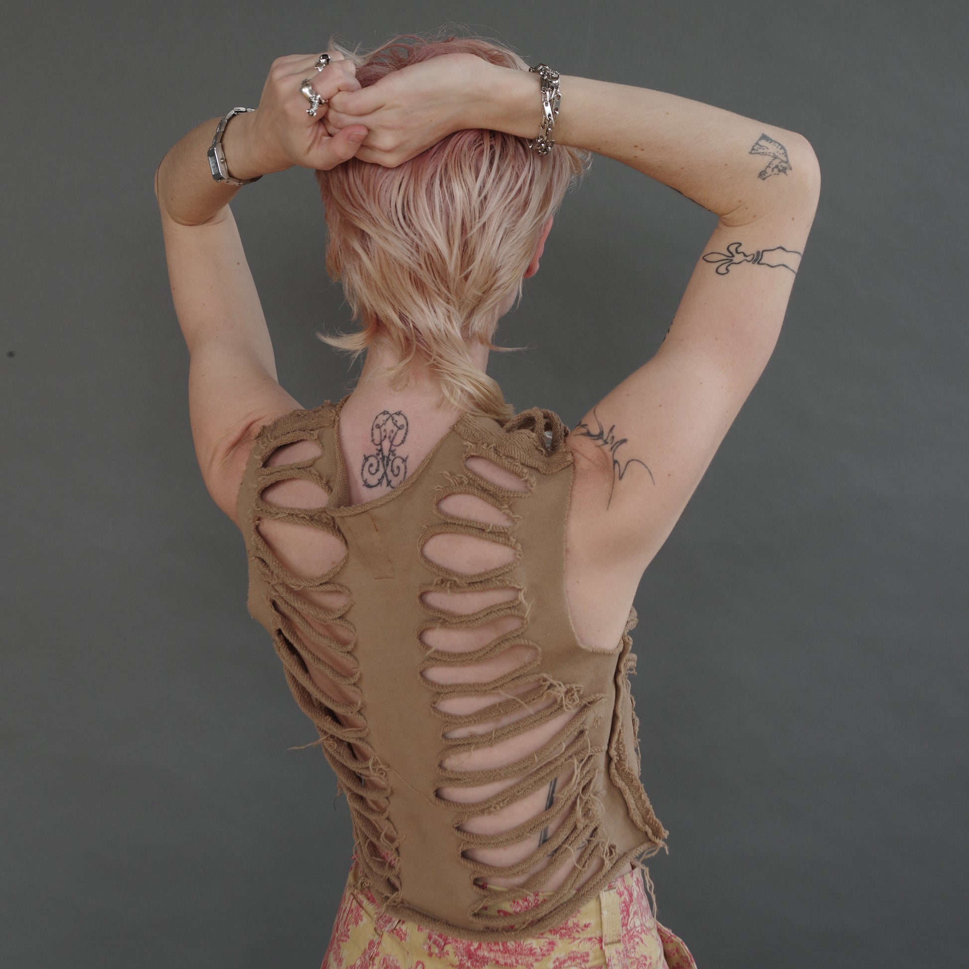 back of model wearing camel colored sliced french terry tank with cuts to look like ribs