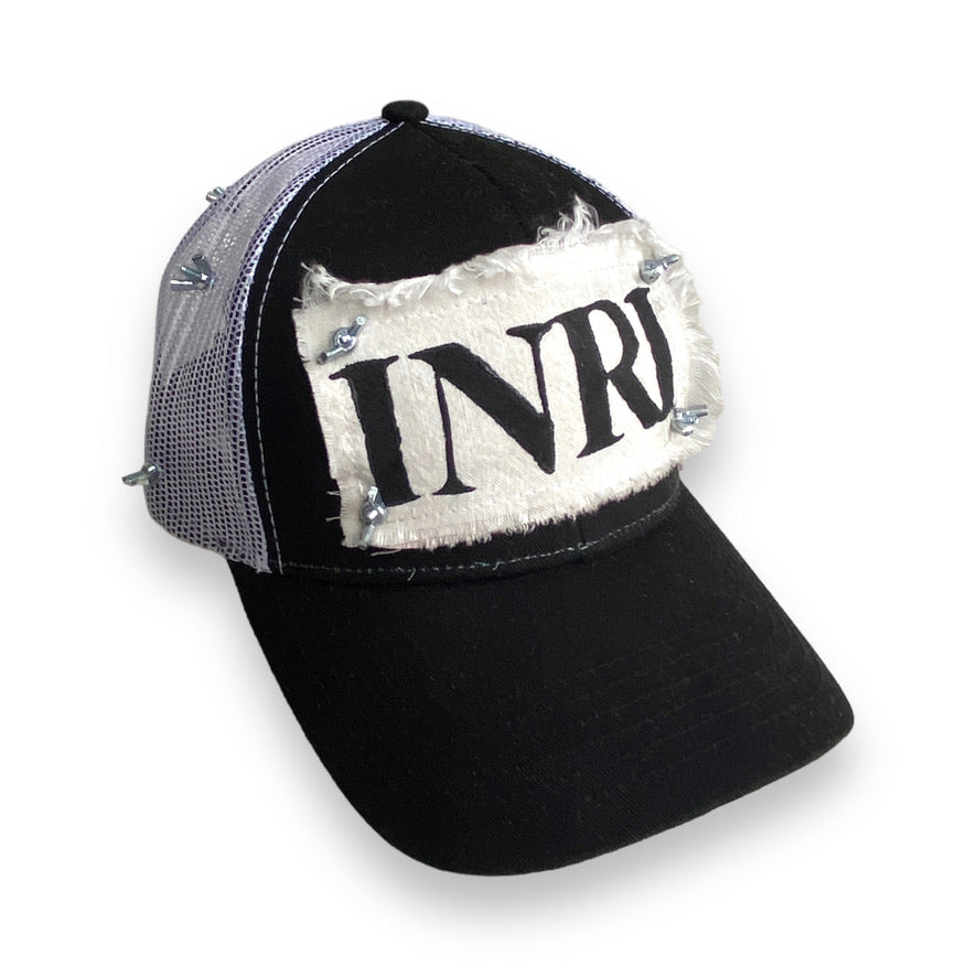 trucker hat with white mesh back, white patch with black INRI stamp, and nuts and bolts affixing the four corners of the patch to the front of the hat and wrapping around in a crown of thorns