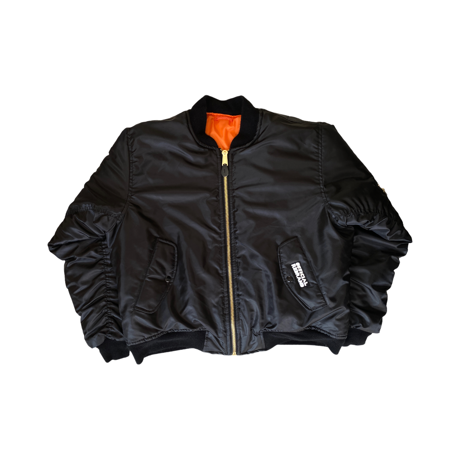 front of black bomber with orange lining and a black tag with white text over the side pocket reading OFFICIAL REBRAND